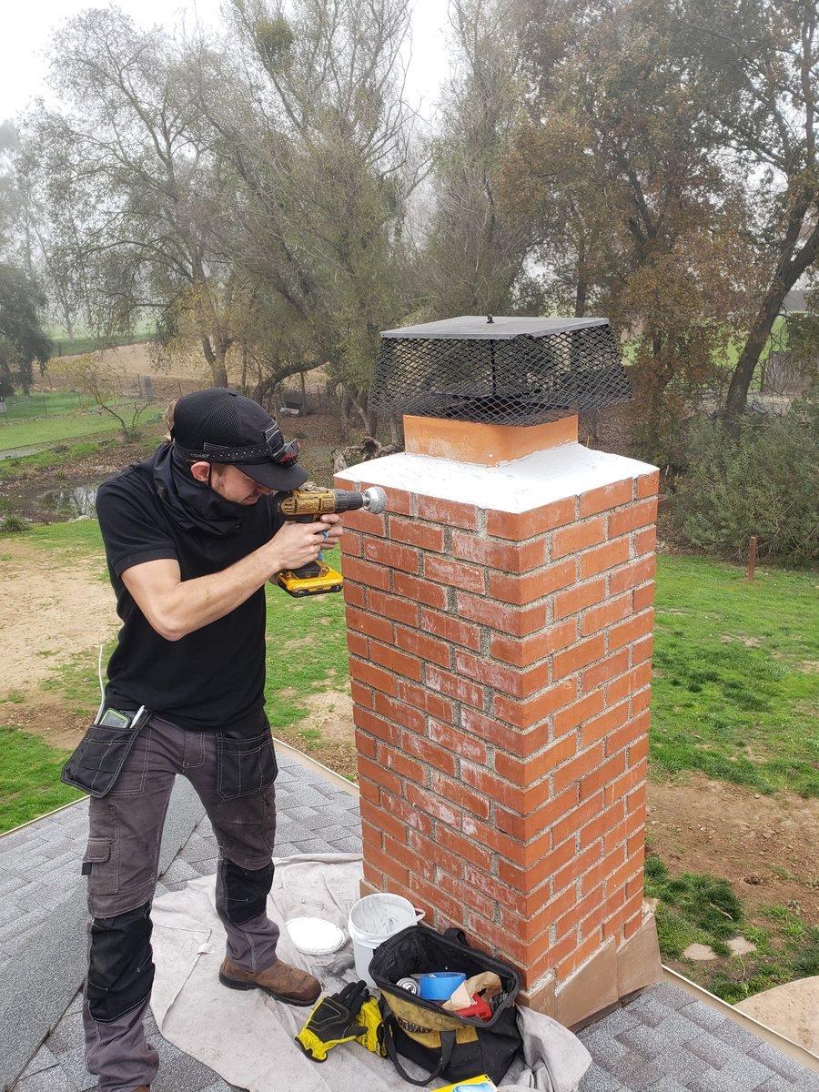 Technician sealing a rebuilt chimney crown and cap