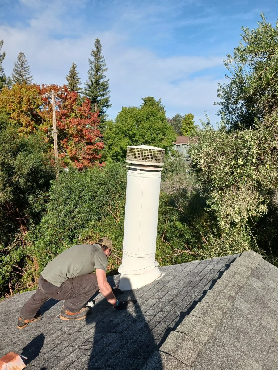 Technician finishing a rebuilt chimney crown on a shingle roof