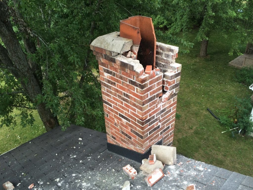Deteriorated brick chimney stack being taken down to sound coursing