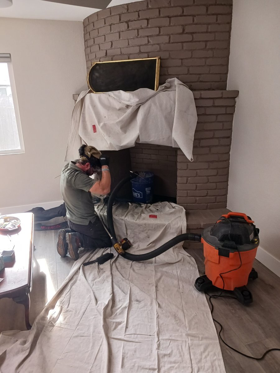 Technician vacuuming soot from a brick firebox with the surrounding floor protected
