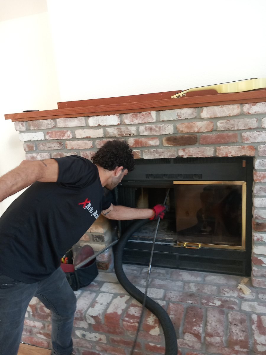 Vacuum hose sealed to a fireplace opening during a chimney sweep