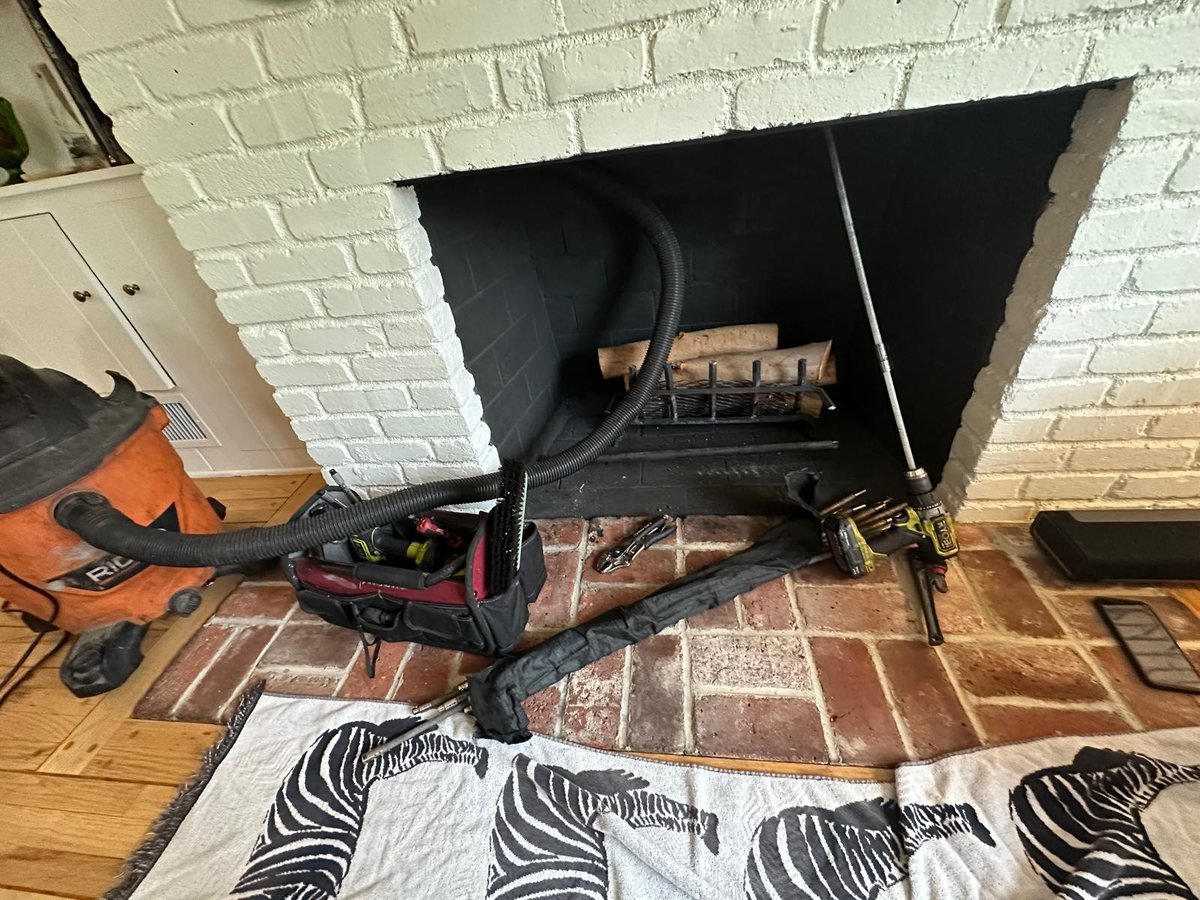 Sweeping equipment set up at a painted white brick fireplace