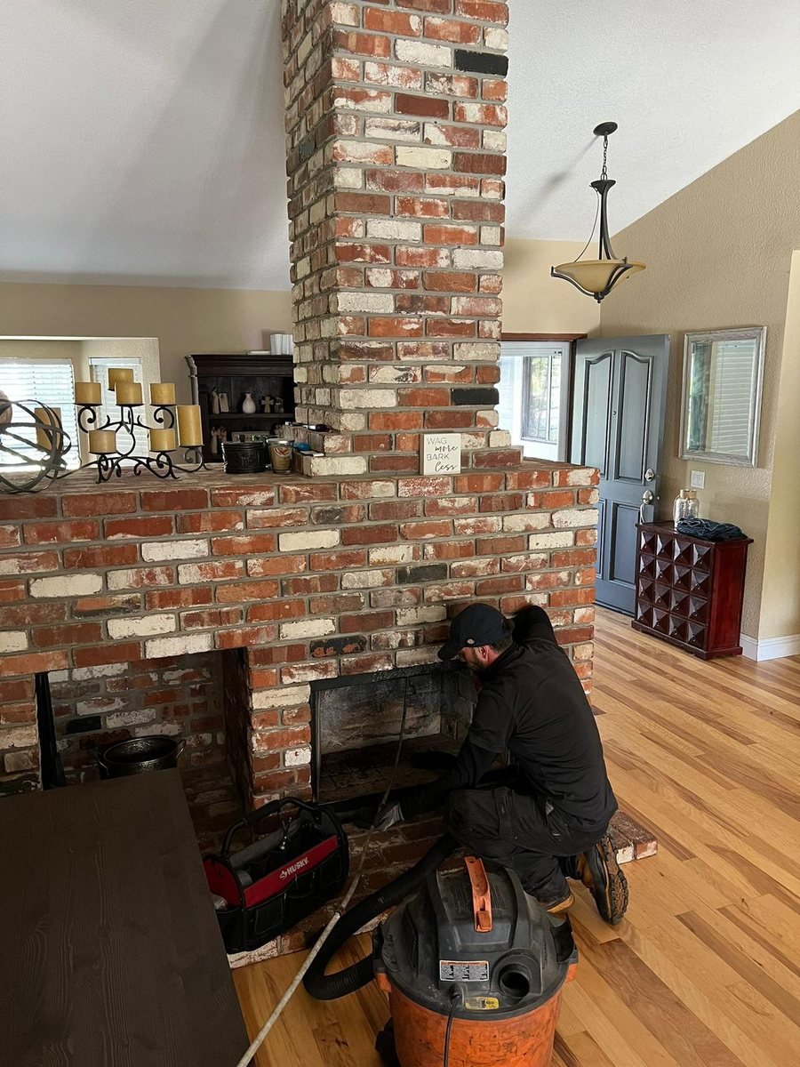Technician sweeping a floor-to-ceiling brick fireplace