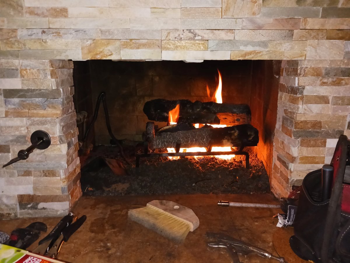 Stone fireplace with a fire burning after servicing
