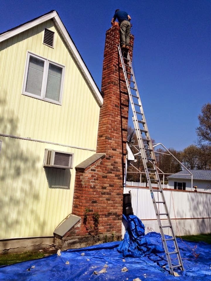 Tall brick chimney stack accessed by ladder for masonry repair